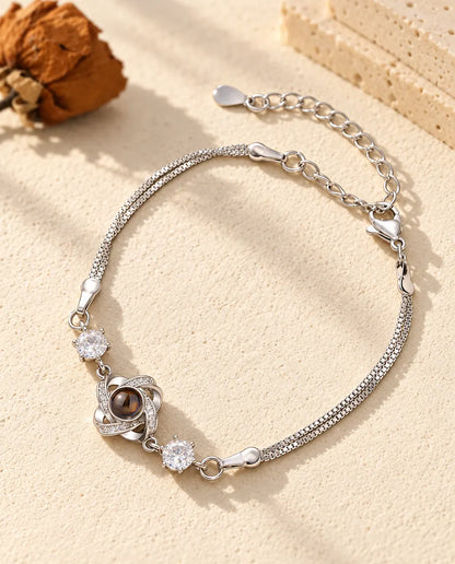 Bracciale con foto dentro argentato con nodo d'amore e due zirconi su doppia catena veneziana, sul gesso crema
