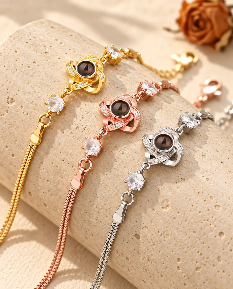 Tre bracciali con nodo d'amore, dorato, color oro rosa e argentato, su un blocco di travertino