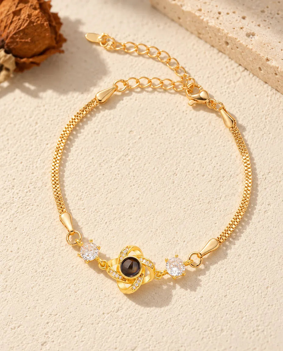 Vista dall'alto del bracciale dorato con nodo d'amore e foto dentro, sul gesso crema