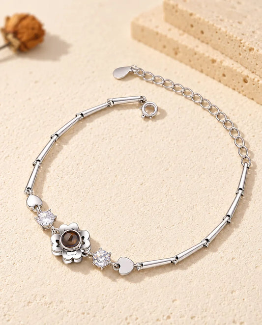 Bracciale con foto dentro argentato con fiore quadrifoglio su catena sottile a barrette, sul gesso crema