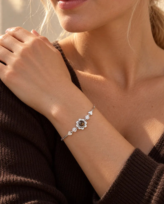Donna con la mano sulla spalla che indossa il bracciale argentato con fiore quadrifoglio e foto dentro