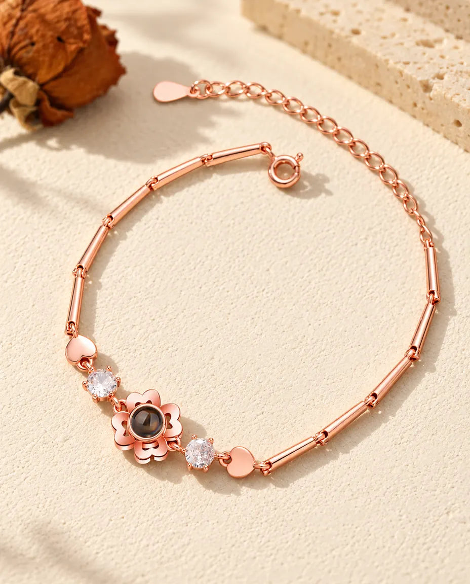 Bracciale color oro rosa con fiore quadrifoglio, zirconi e piccoli cuori lucidi lungo la catena