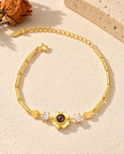 Vista dall'alto del bracciale dorato con fiore quadrifoglio e foto dentro, sul gesso crema