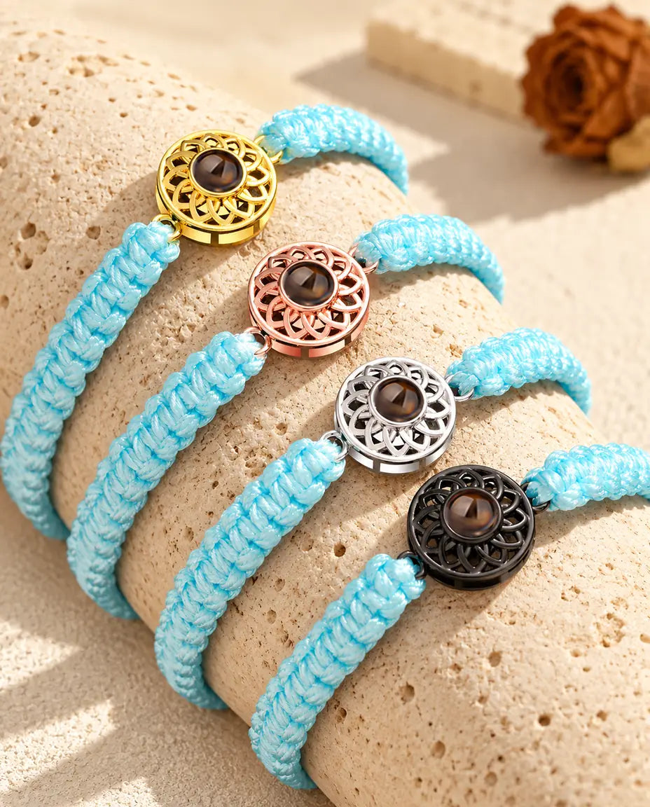 Bracciali con cordino intrecciato azzurro allineati su un blocco di travertino, uno per ogni colore del charm