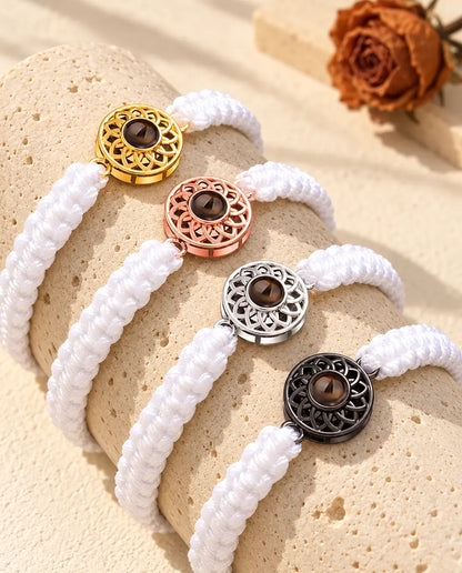 Quattro bracciali con cordino intrecciato bianco e charm tondi in tutti e quattro i colori, sul travertino