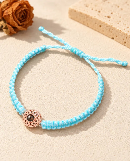Charm tondo color oro rosa su cordino intrecciato azzurro con nodo scorrevole regolabile