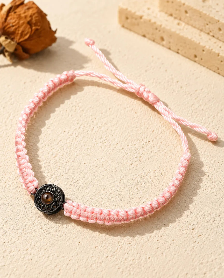 Bracciale con cordino intrecciato rosa e charm tondo nero che custodisce la pietra marrone con la foto
