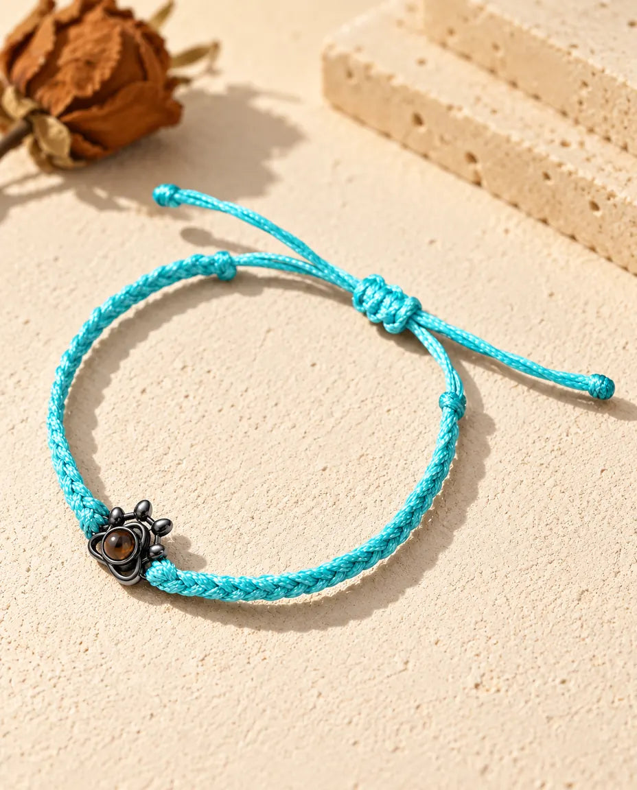 Charm a zampa nero su cordino intrecciato blu con la piccola pietra marrone al centro