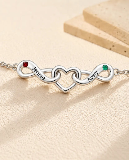 Bracciale Infinito Personalizzato 2 Nomi - due nodi infiniti attorno a un cuore e due pietre portafortuna - primo piano dei nomi incisi e delle pietre di nascita