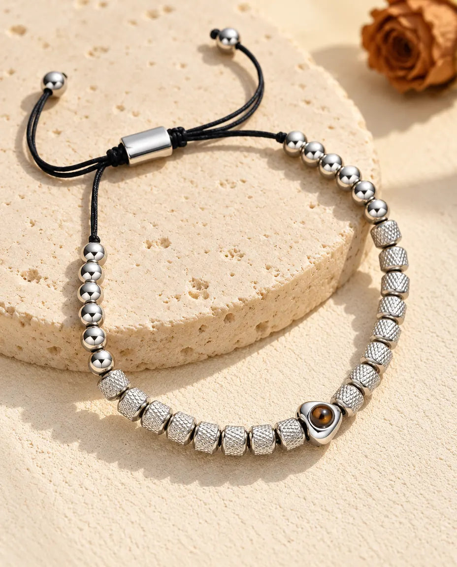 Bracciale di perline con foto dentro argentato, perla a cuore e perline zigrinate, su una lastra di travertino