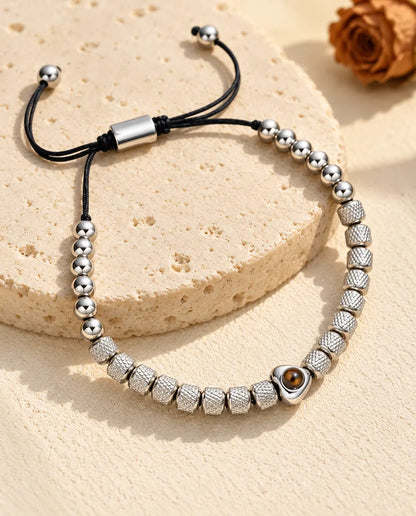 Bracciale di perline con foto dentro argentato, perla a cuore e perline zigrinate, su una lastra di travertino