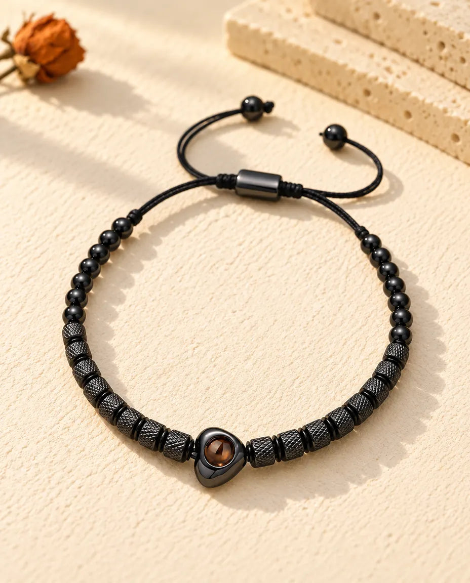 Vista dall'alto del bracciale di perline nero con cuore e foto dentro, sul gesso crema