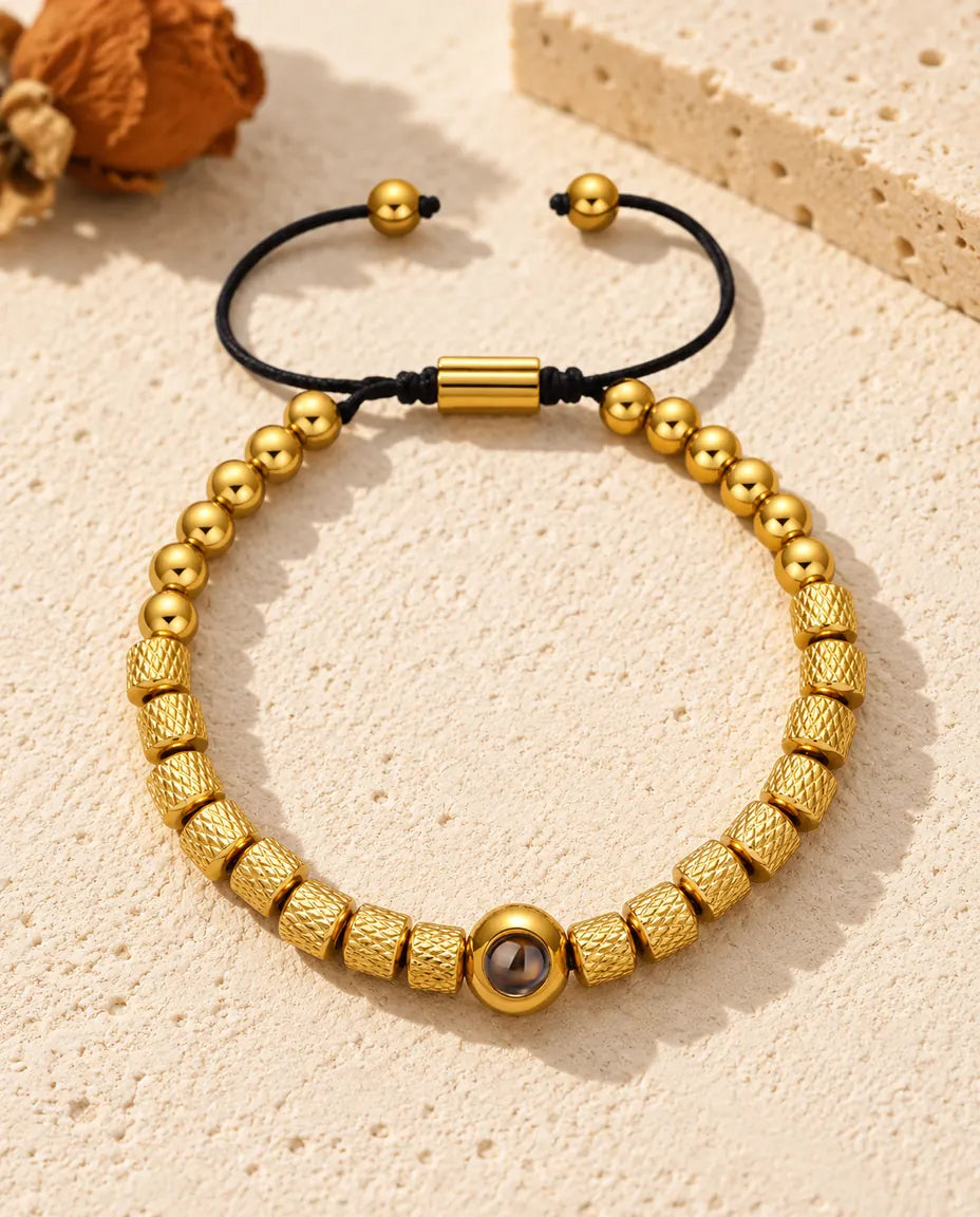 Bracciale di perline con foto dentro dorato, perline zigrinate e cordino scorrevole, sul gesso crema