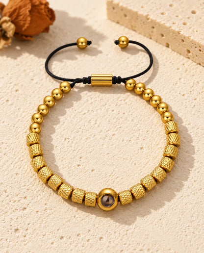 Bracciale di perline con foto dentro dorato, perline zigrinate e cordino scorrevole, sul gesso crema