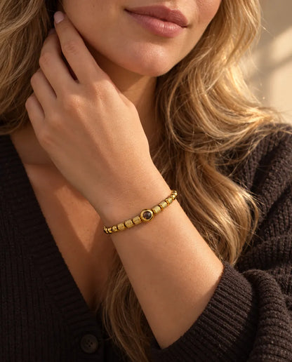 Donna che si sfiora il collo e indossa il bracciale di perline zigrinate dorato con foto dentro
