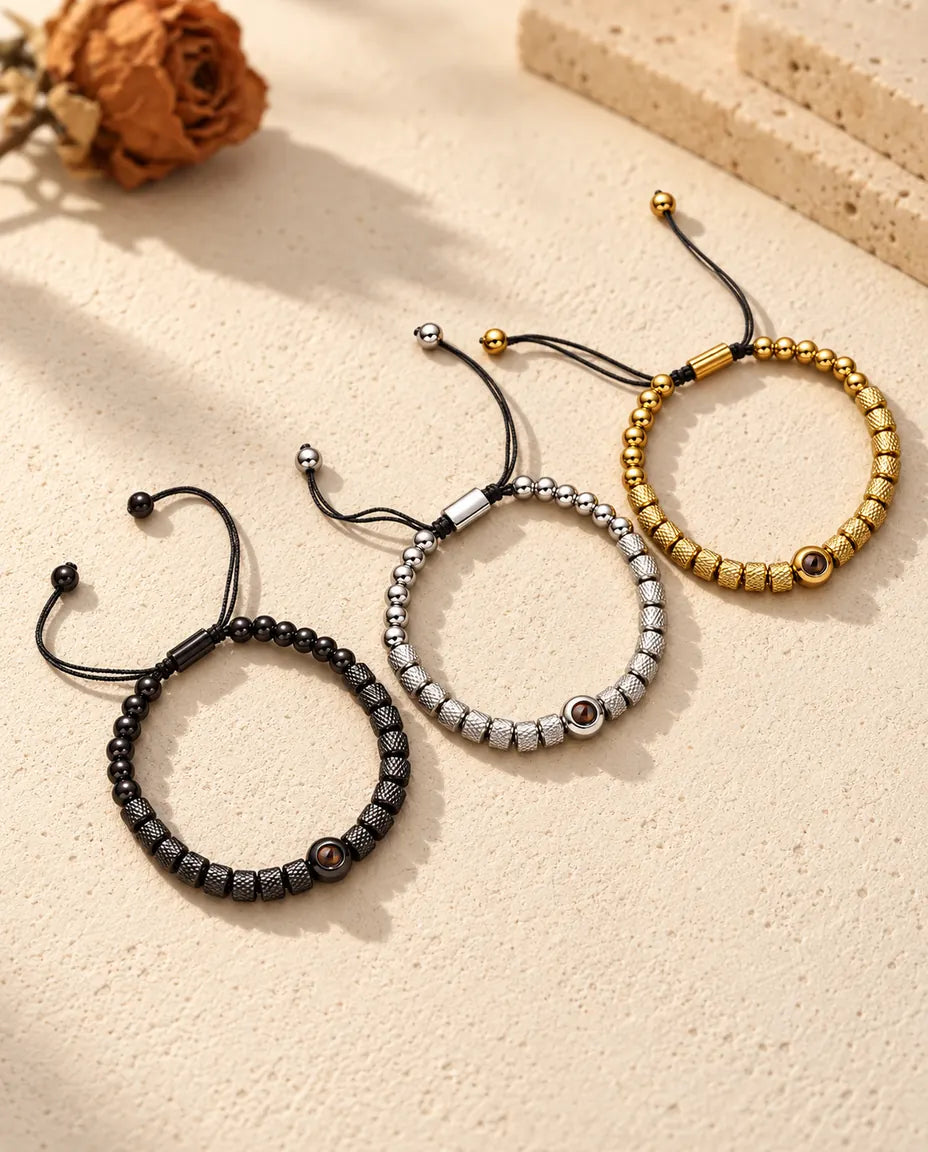 Tre bracciali di perline zigrinate con foto dentro affiancati: dorato, argentato e nero
