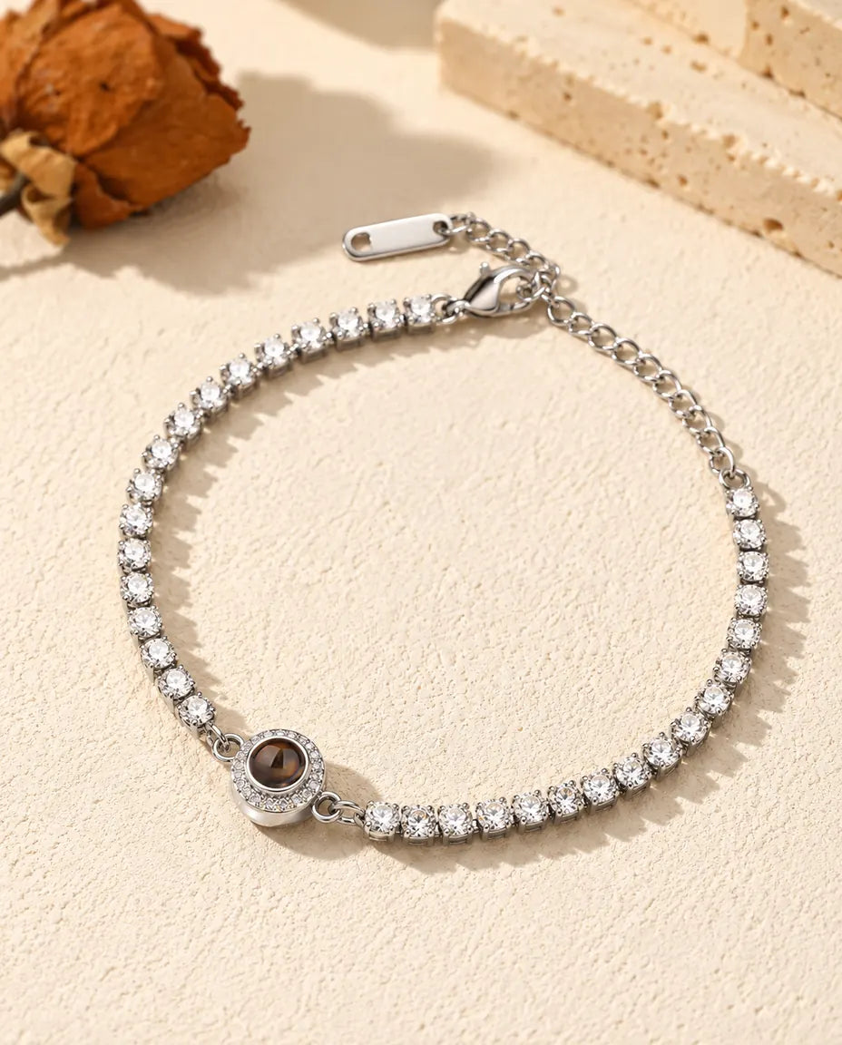 Bracciale tennis con foto dentro argentato con charm halo, adagiato sul gesso crema