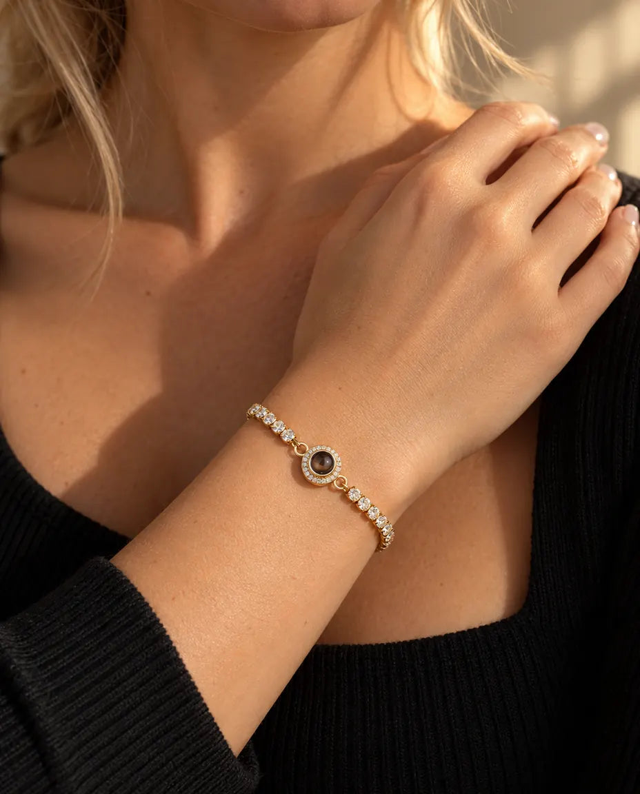 Primo piano del bracciale tennis dorato con charm halo al polso, vicino alla clavicola