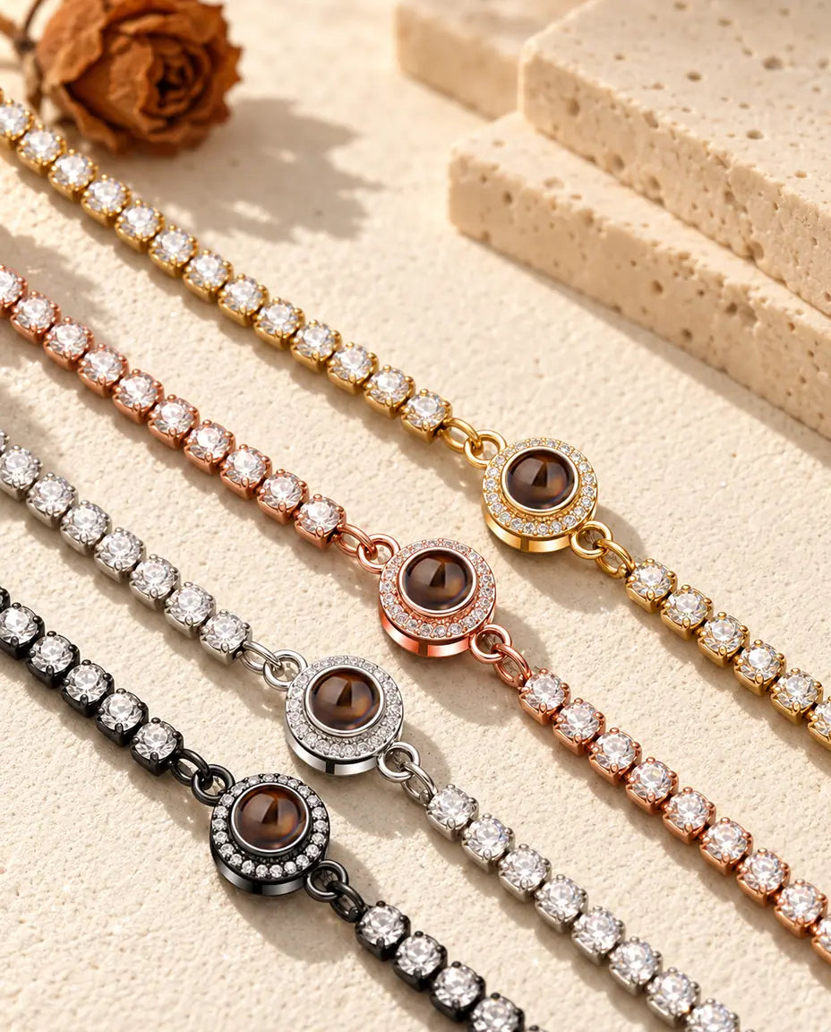 Quattro bracciali tennis con charm halo affiancati: dorato, color oro rosa, argentato e nero