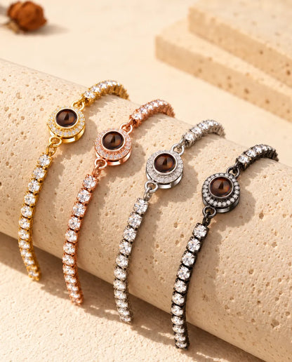 Quattro bracciali tennis con foto dentro appoggiati su un blocco di travertino, uno per colore
