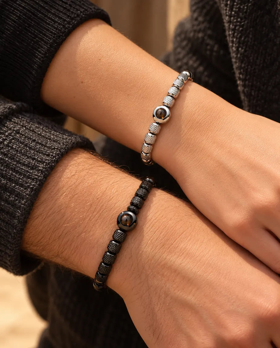 Primo piano dei polsi di lui e di lei con i bracciali di perline argentato e nero abbinati