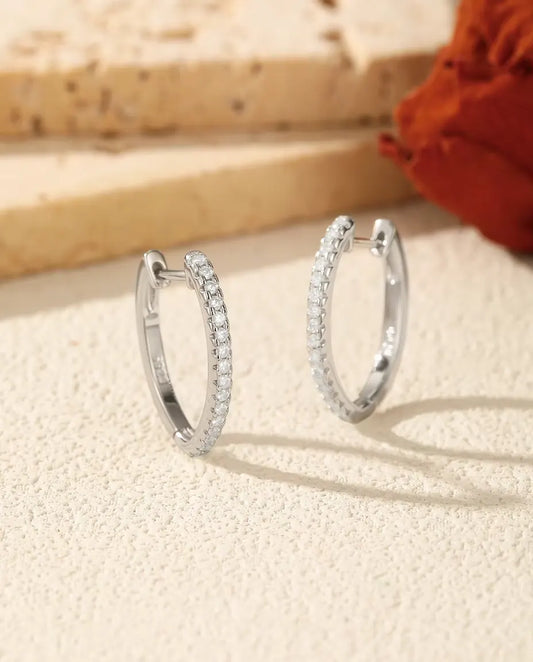 Orecchini a Cerchio con Moissanite a U in Argento 925 - la coppia affiancata su una superficie chiara ruvida