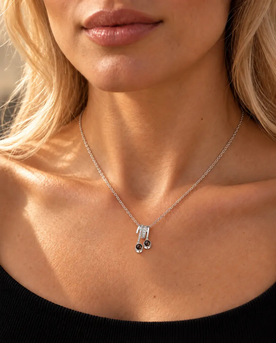 Donna con un top nero in maglia che indossa la collana argentata con due pietre e due foto dentro