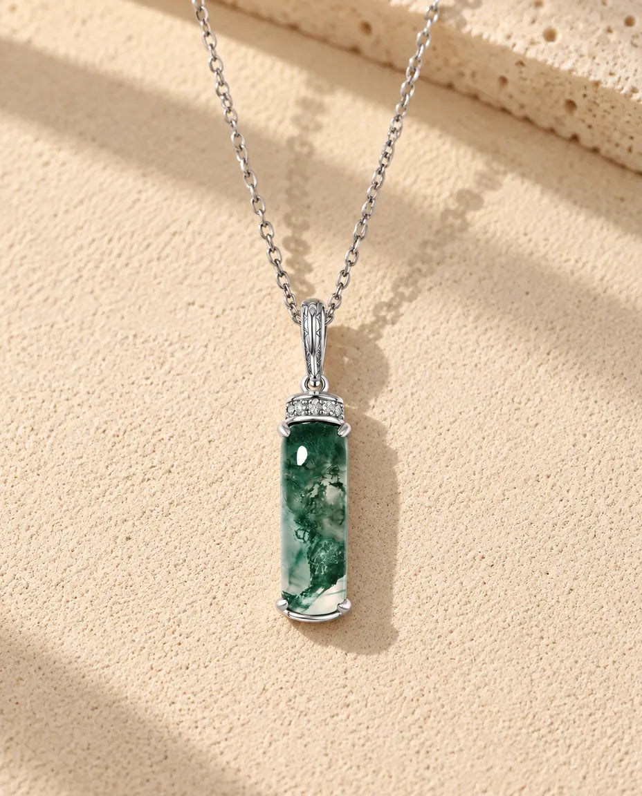 Collana Agata Muschiata Barretta Lunga in Argento 925 - appoggiata su una superficie chiara ruvida accanto a un blocco di travertino
