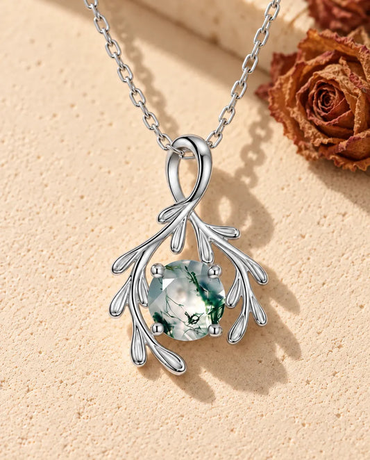 Collana Agata Muschiata Rami in Argento 925 - appoggiata su una superficie chiara ruvida accanto a un blocco di travertino