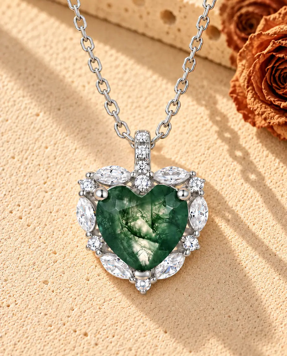 Collana Agata Muschiata Cuore Halo in Argento 925 - appoggiata su una superficie chiara ruvida accanto a un blocco di travertino