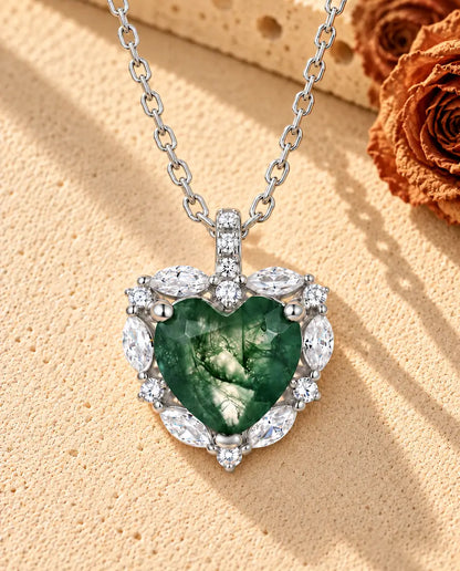 Collana Agata Muschiata Cuore Halo in Argento 925 - appoggiata su una superficie chiara ruvida accanto a un blocco di travertino