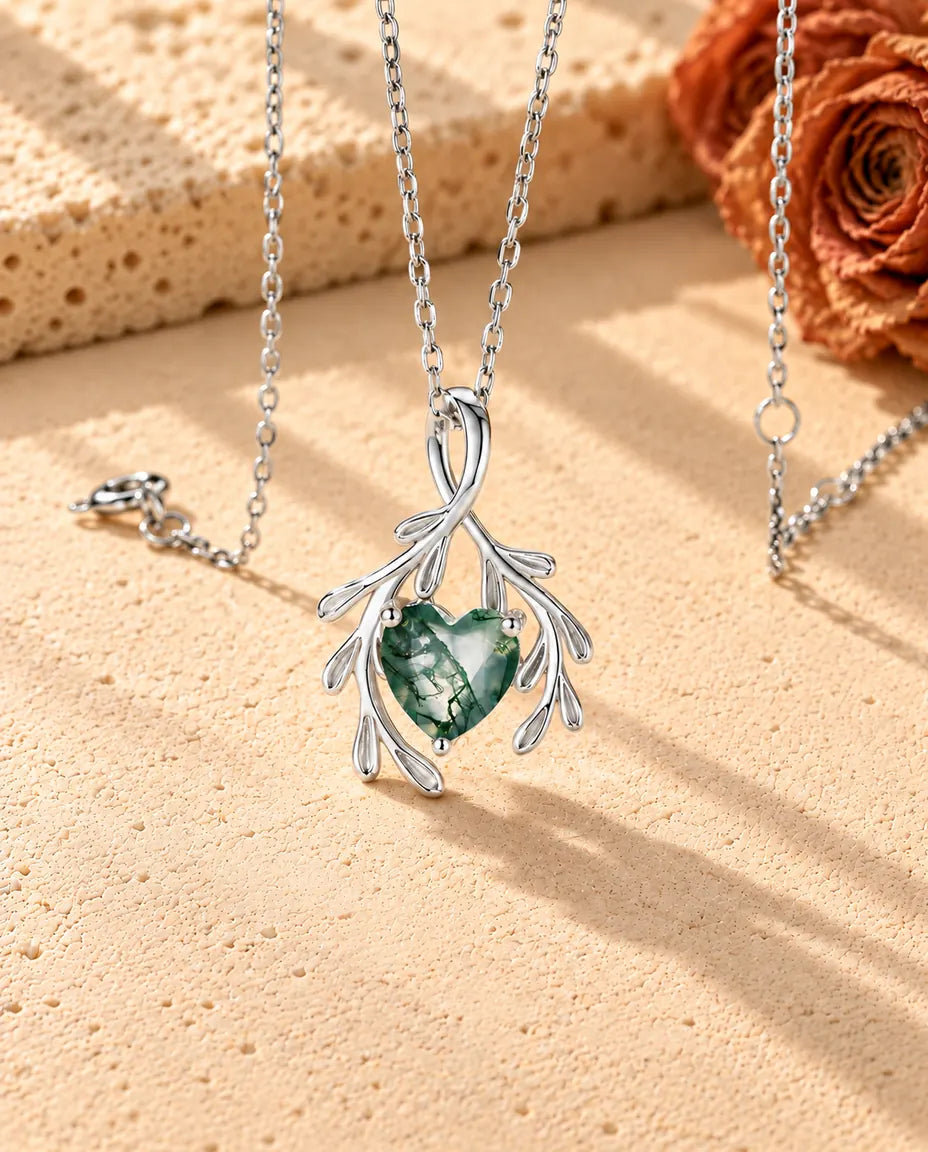 Collana Agata Muschiata Cuore con Rami in Argento 925 - vista di tre quarti su una superficie chiara ruvida