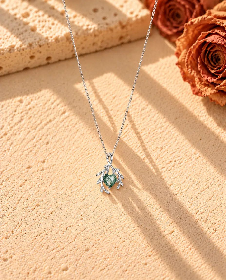 Collana Agata Muschiata Cuore con Rami in Argento 925 - la collana intera distesa a lunga V su una superficie chiara ruvida