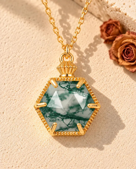 Collana Agata Muschiata Esagonale in Argento 925 Placcato Oro - appoggiata su una superficie chiara ruvida accanto a un blocco di travertino
