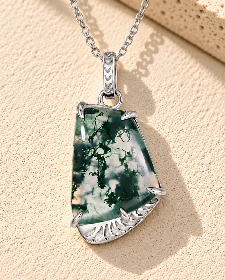 Collana Agata Muschiata Forma Libera in Argento 925 - appoggiata su una superficie chiara ruvida accanto a un blocco di travertino
