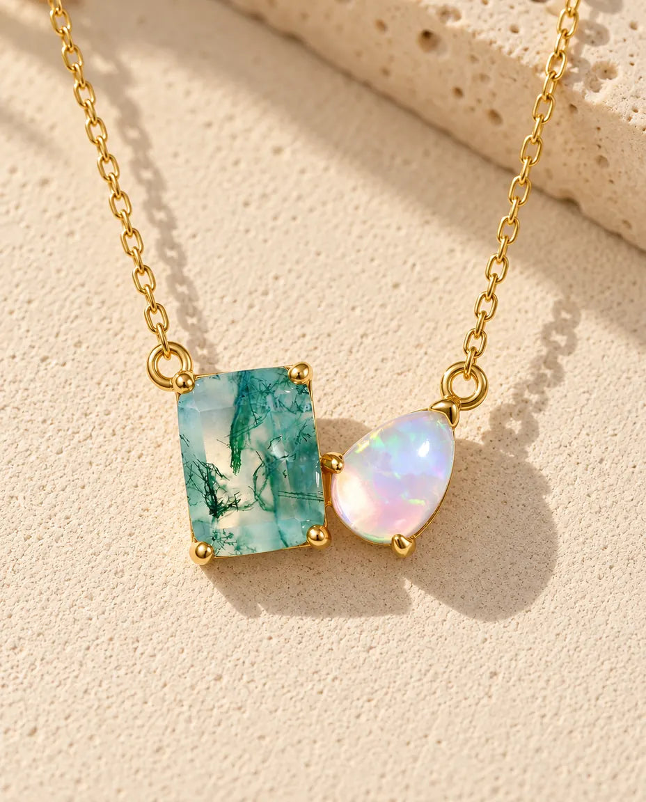 Collana Agata Muschiata e Opale in Argento 925 Placcato Oro - appoggiata su una superficie chiara ruvida accanto a un blocco di travertino