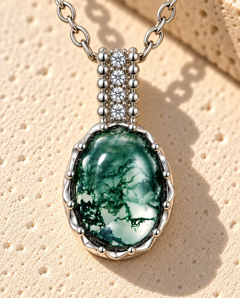 Collana Agata Muschiata Ovale in Argento 925 - appoggiata su una superficie chiara ruvida accanto a un blocco di travertino