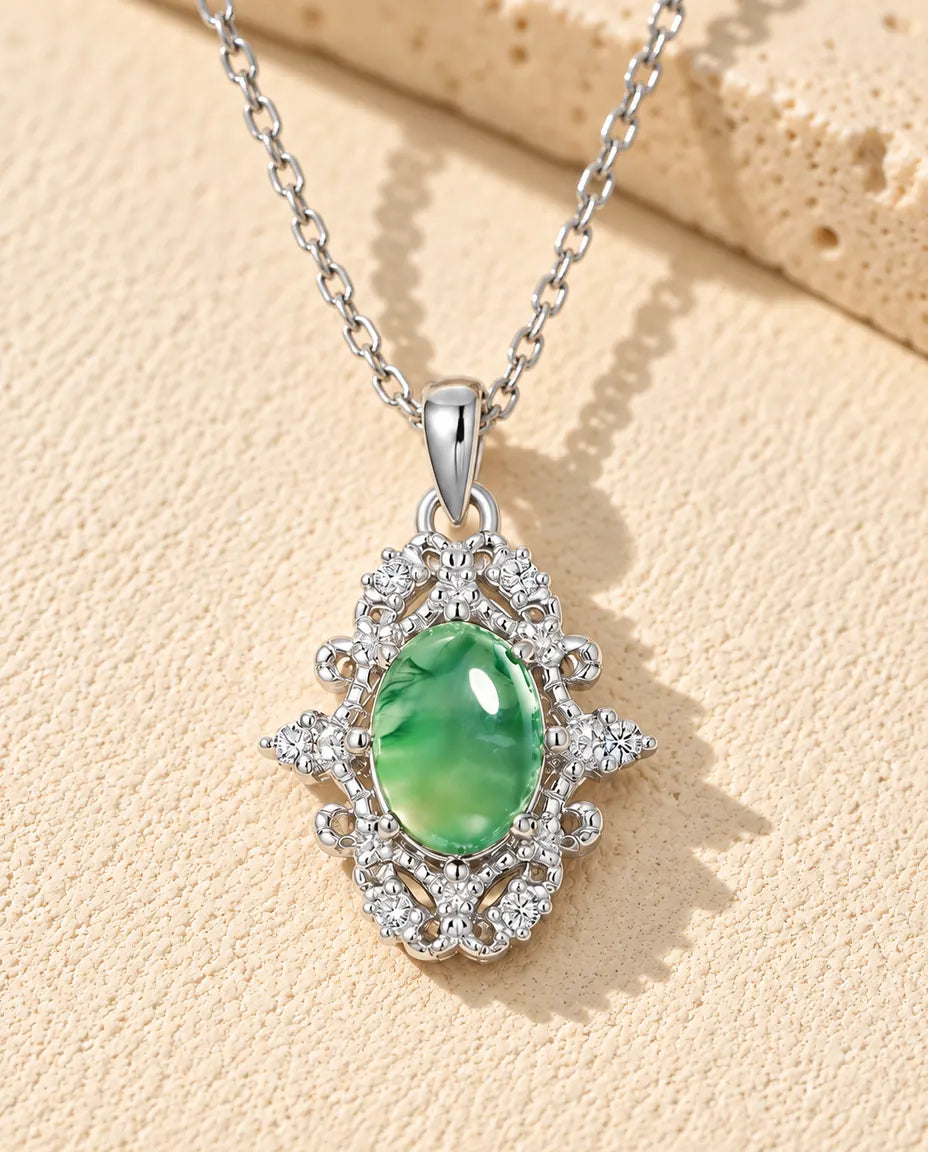 Collana Agata Muschiata Ovale in Argento 925 - appoggiata su una superficie chiara ruvida accanto a un blocco di travertino