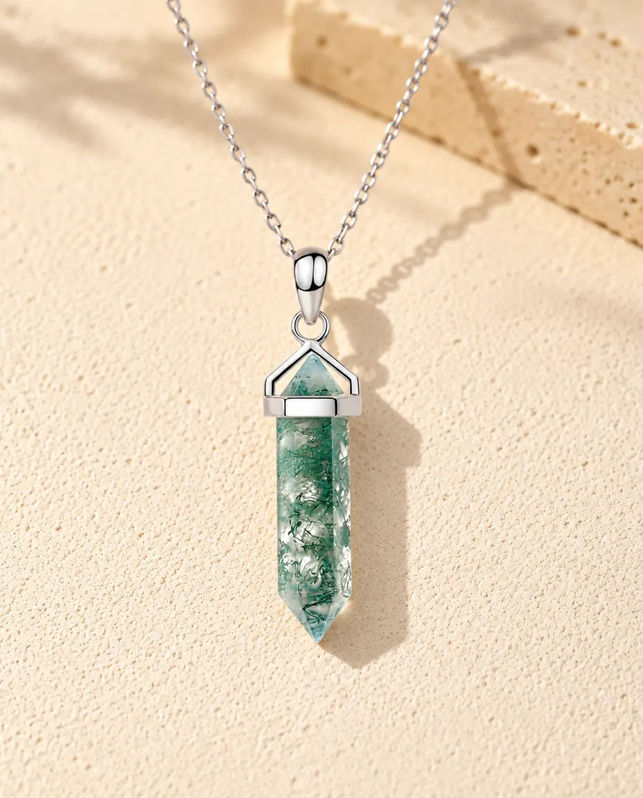 Collana Agata Muschiata Punta Esagonale in Argento 925 - appoggiata su una superficie chiara ruvida accanto a un blocco di travertino