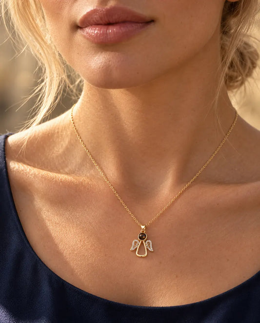 Donna con un top blu navy che indossa la collana ad angelo dorata con foto dentro