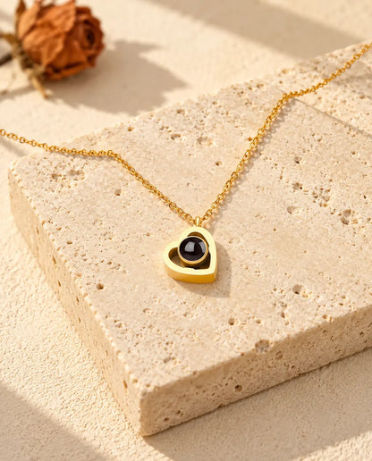 Collana doppio cuore con foto dentro dorata distesa su un blocco di travertino