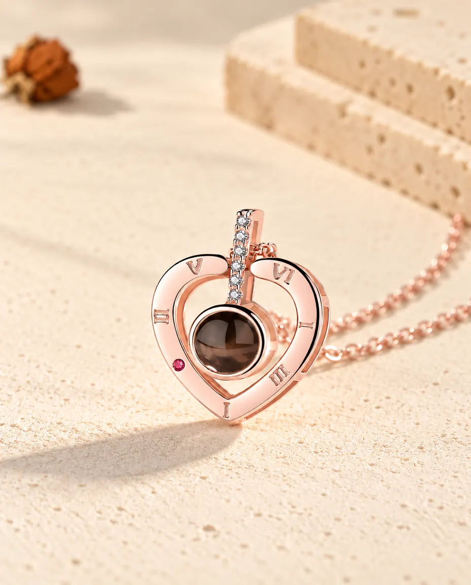 Primo piano del ciondolo a cuore color oro rosa con la barretta di zirconi e i numeri romani