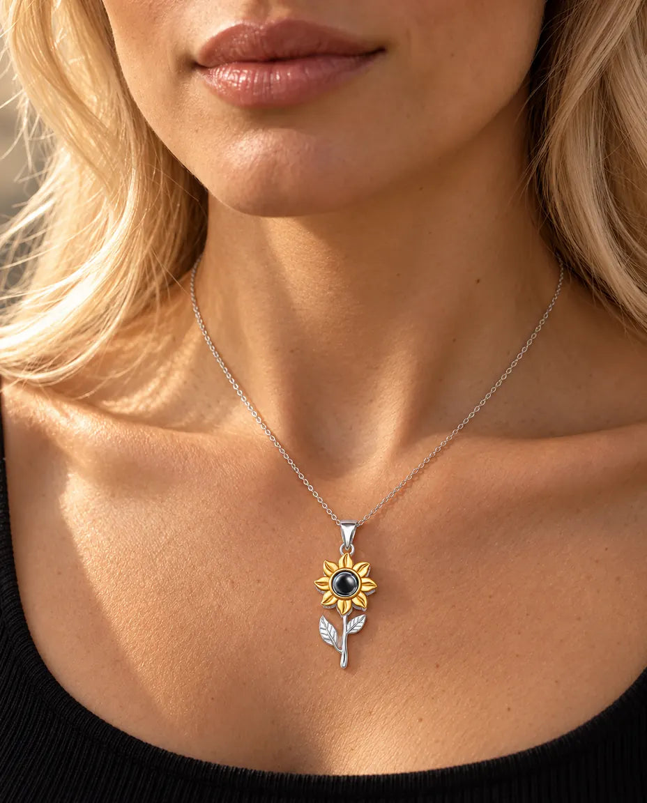 Donna con un top nero che indossa la collana a girasole con stelo in argento e foto dentro