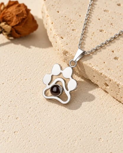Collana con foto dentro personalizzata a forma di zampa in argento 925 appoggiata su una lastra di travertino