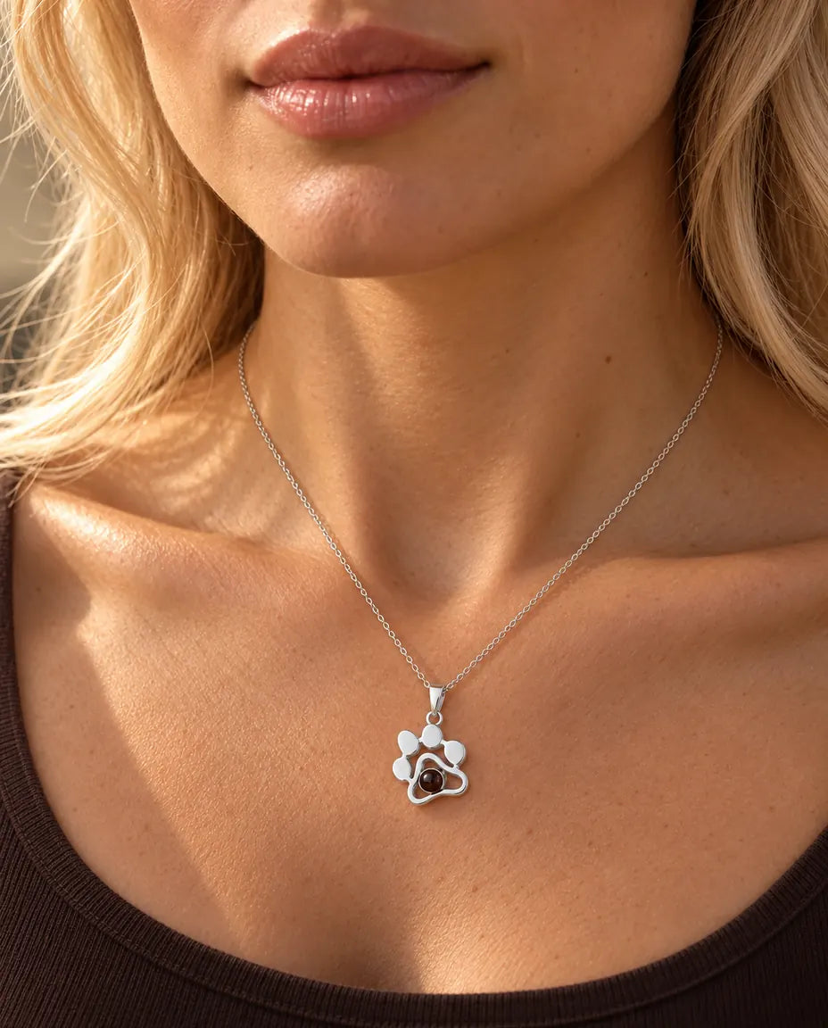 Donna con un top marrone che indossa la collana a zampa in argento con la foto del suo animale