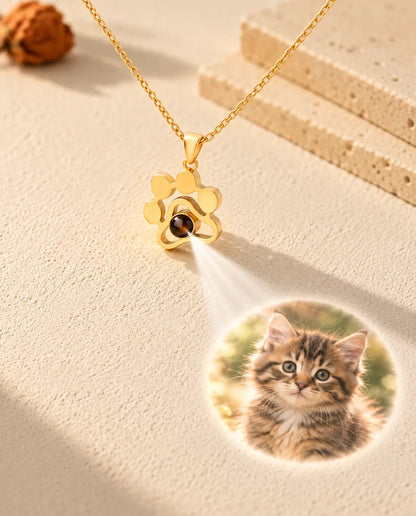 Collana a zampa dorata che proietta la foto di un gattino sul gesso color crema