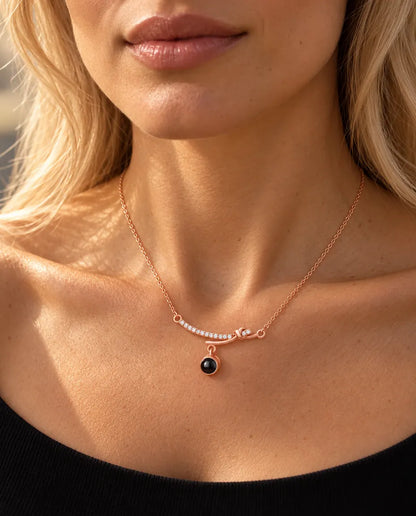 Donna con maglia nera che indossa la collana a barra curva color oro rosa all'altezza della clavicola