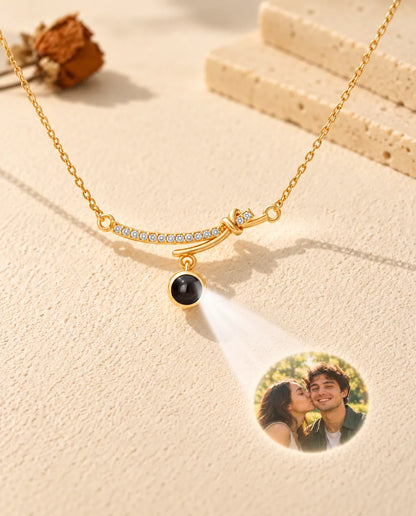 Collana dorata a barra curva che proietta la foto di una coppia su una parete di intonaco crema
