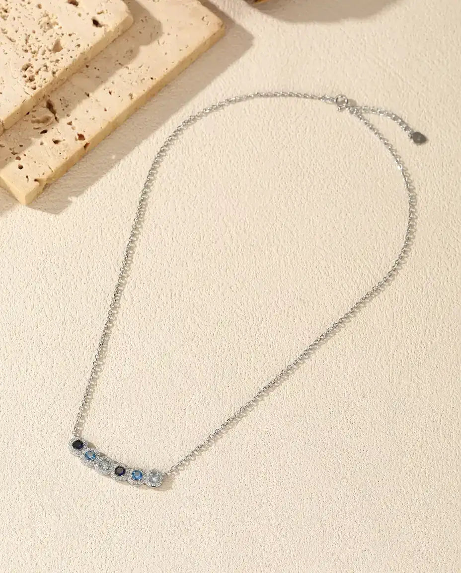 Collana Barra Sfumata Blu - sei pietre blu con halo di pavé, barra curva 34 mm, argento 925, catena 40+5 cm