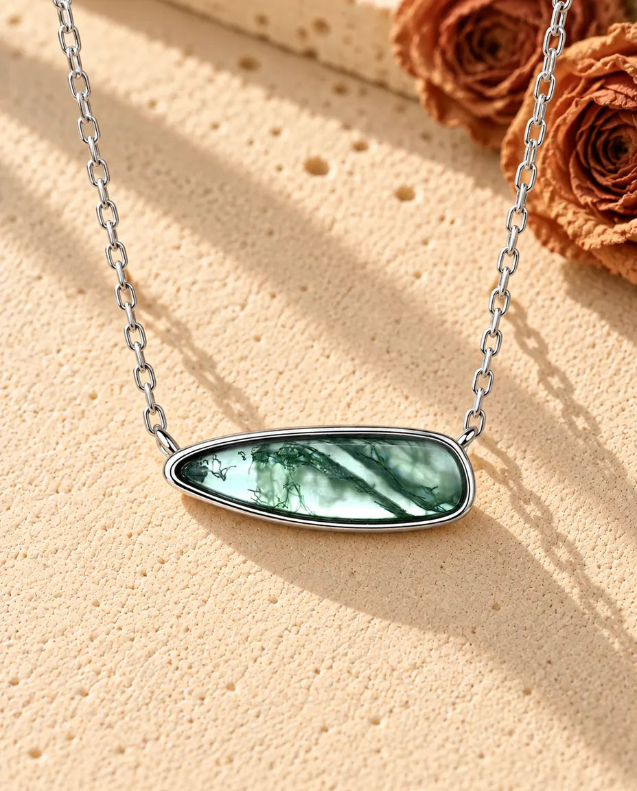 Collana Barretta Agata Muschiata in Argento 925 - appoggiata su una superficie chiara ruvida accanto a un blocco di travertino